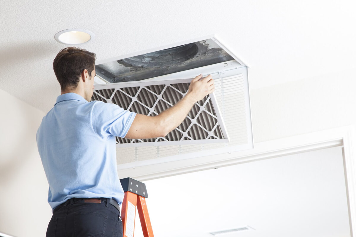 Person replacing home air filter in HVAC system return vent with arrows showing proper direction