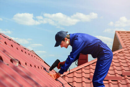 Licensed roofing contractor inspecting residential roof with safety equipment and tools