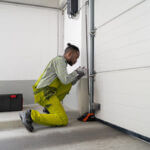 Homeowner performing maintain your garage door maintenance by lubricating hinges and checking safety sensors