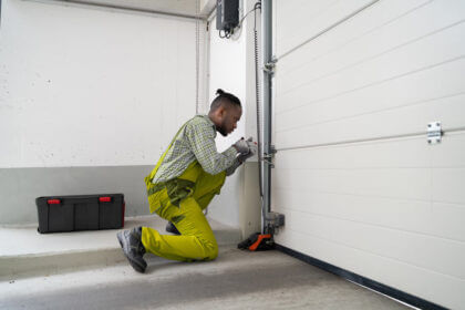 Homeowner performing maintain your garage door maintenance by lubricating hinges and checking safety sensors