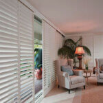 Modern cedar shutters installed on white farmhouse exterior with board and batten style design