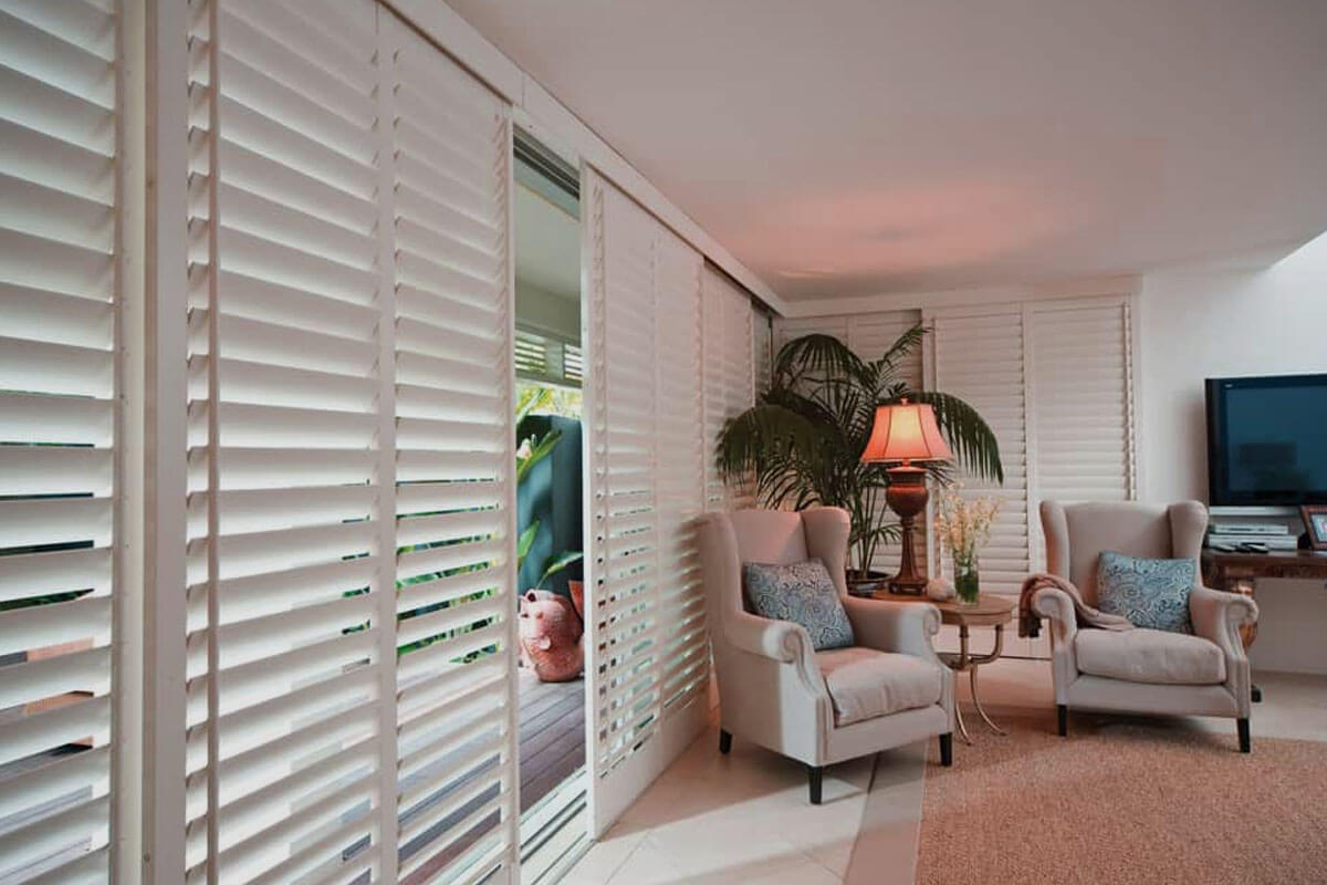 Modern cedar shutters installed on white farmhouse exterior with board and batten style design