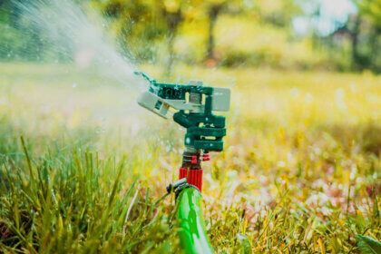 Professional sprinkler repair technician fixing irrigation system in Golden Colorado backyard