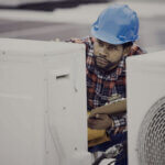 HVAC technician performing seasonal maintenance on outdoor unit with tools and checklist for energy efficiency
