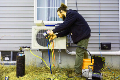 Professional heat pump installation with outdoor unit being installed by HVAC technician for home heating and cooling