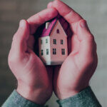 HomeAssure Admin home warranty technician repairing appliance with tools and service contract paperwork on kitchen counter