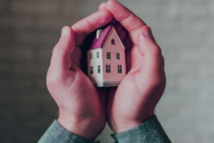 HomeAssure Admin home warranty technician repairing appliance with tools and service contract paperwork on kitchen counter