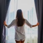 Custom blackout curtains hanging in bedroom window blocking light for better sleep and energy savings