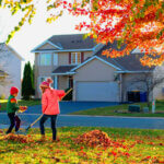 Homeowner cleaning gutters and checking roof as part of essential fall home maintenance tips before winter weather arrives