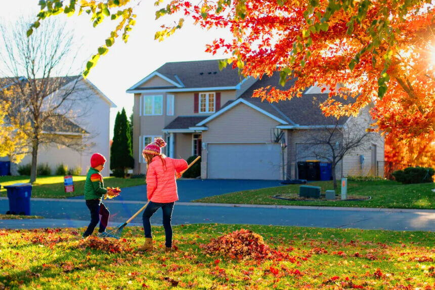Homeowner cleaning gutters and checking roof as part of essential fall home maintenance tips before winter weather arrives