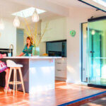 Modern glass bifold doors opening to outdoor patio creating seamless indoor-outdoor living space with natural light