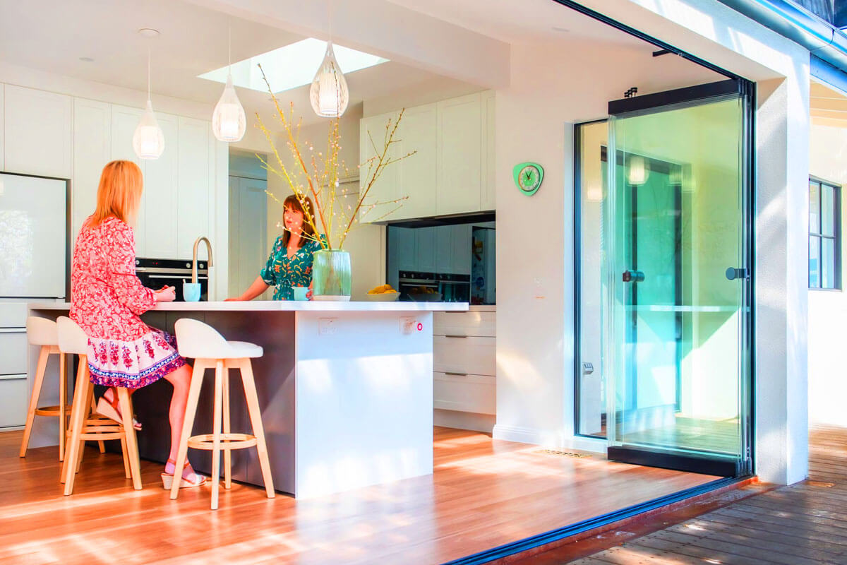 Modern glass bifold doors opening to outdoor patio creating seamless indoor-outdoor living space with natural light