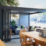 Person installing bifold door track and pivot brackets with drill and level tools for proper alignment