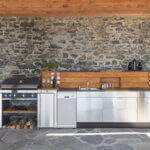 Affordable outdoor modular kitchen with stainless steel grill island and storage cabinets in modern backyard setting