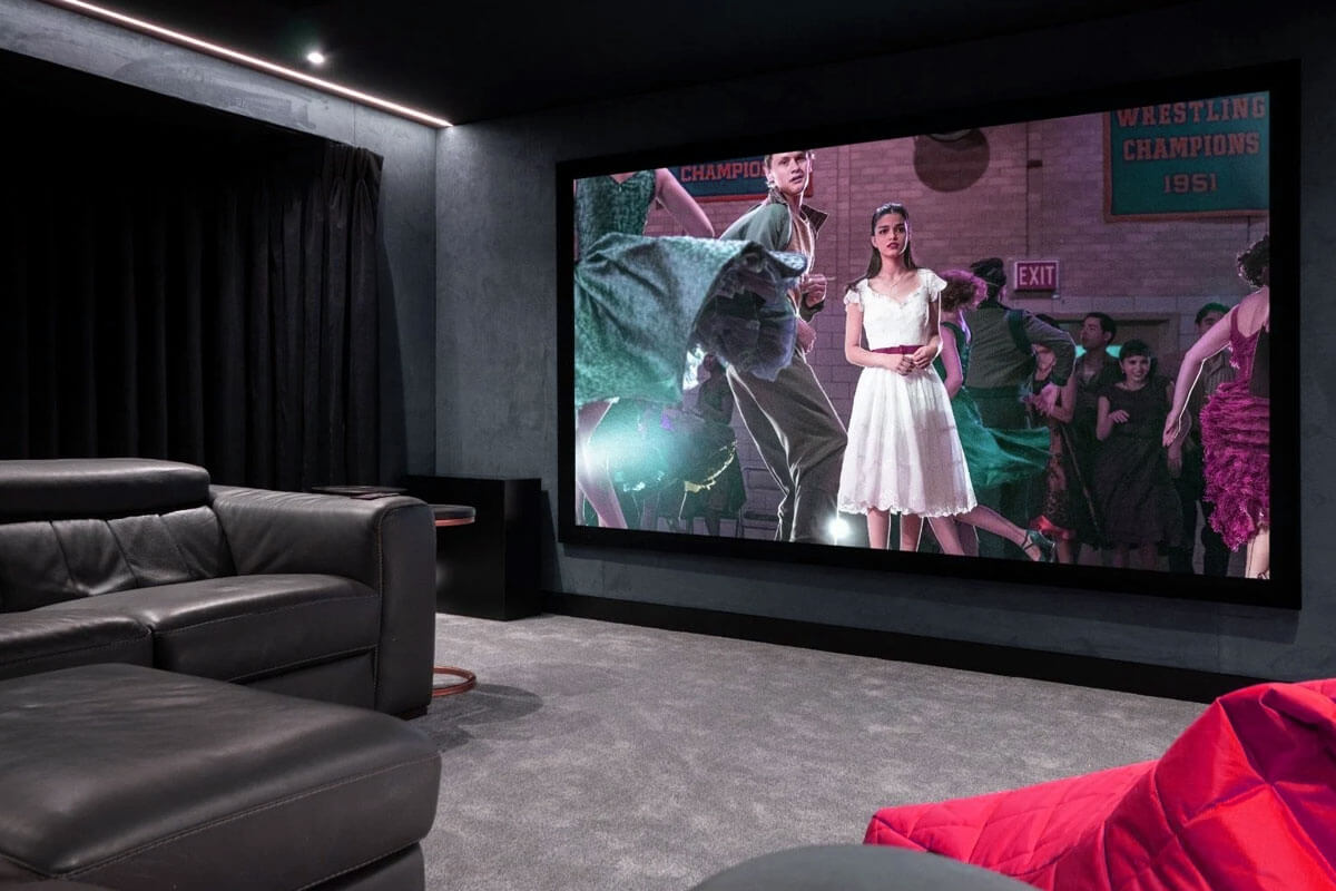 Perfect home theater setup with large screen surround sound speakers comfortable seating and controlled lighting in dark room