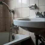 Bathroom showing low water pressure from shower head with pressure gauge visible on pipe demonstrating how to improve water pressure in your home