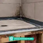 Shower pan construction corner with waterproof membrane and drain base exposed