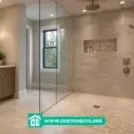 Custom curbless shower pan in a modern walk-in bathroom with glass enclosure, large tile walls, pebble floor, and linear drain