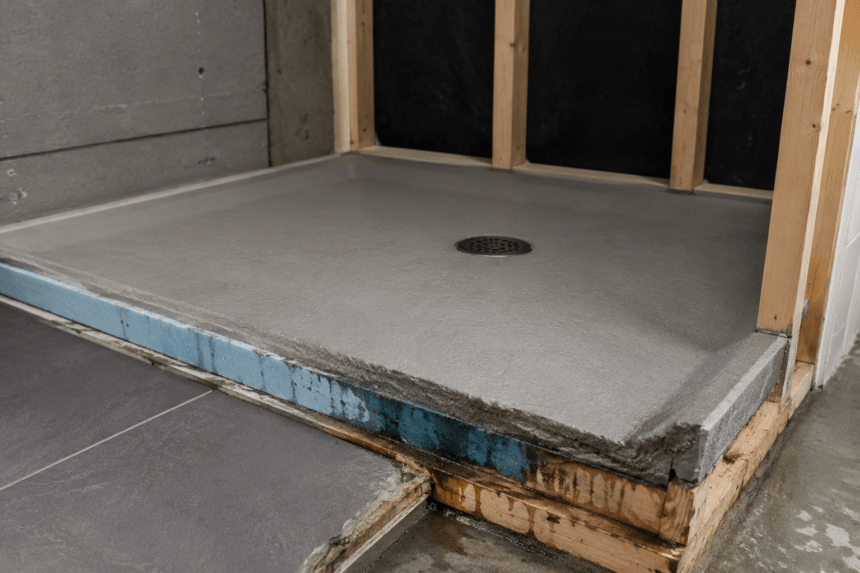 pre slope shower pan base with visible water damage at edges and exposed wood framing in unfinished bathroom