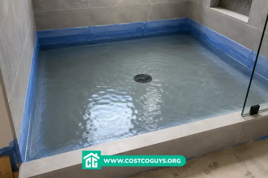 Waterproofing shower base flood test with filled tiled shower pan and blue waterproof membrane along walls