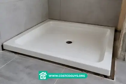 Tape measure across an acrylic shower pan checking width and depth before installation